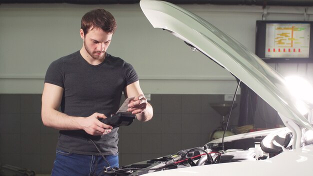car-mechanic-using-electrical-tool-testing-car-system-garage-repair